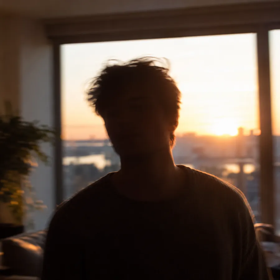 A man standing in front of a bright window, his face in dark shadow